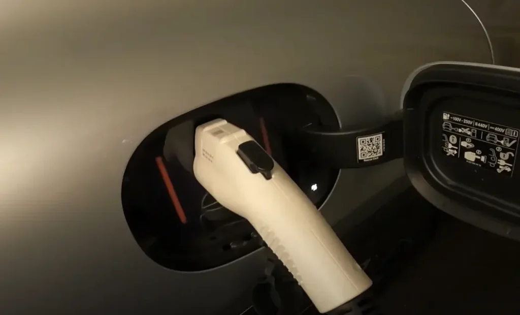 A close up photo using the Lectron Level 1 EV Charger J1772 connector to charge an EV, the image shows shows its dust cover and secure latch mechanism when charging an EV