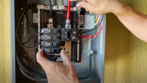 James a licensed electrician and certified EV charger installer installing a circuit breaker in an electrical panel to protect an EV charger circuit