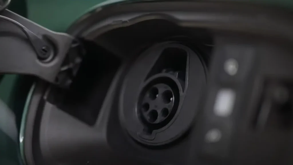 Close-up of the 2025 Bentley Continental GT Hybrid SAE J1772 AC charging port, set flush in the dark green body panel.