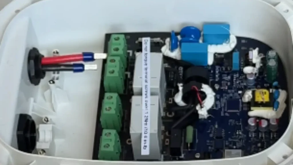 Close-up view of the dark blue Printed Circuit Board (PCB) from an Emporia EV charger, showing capacitors, inductors, ICs, and power electronics for charging control and power delivery.