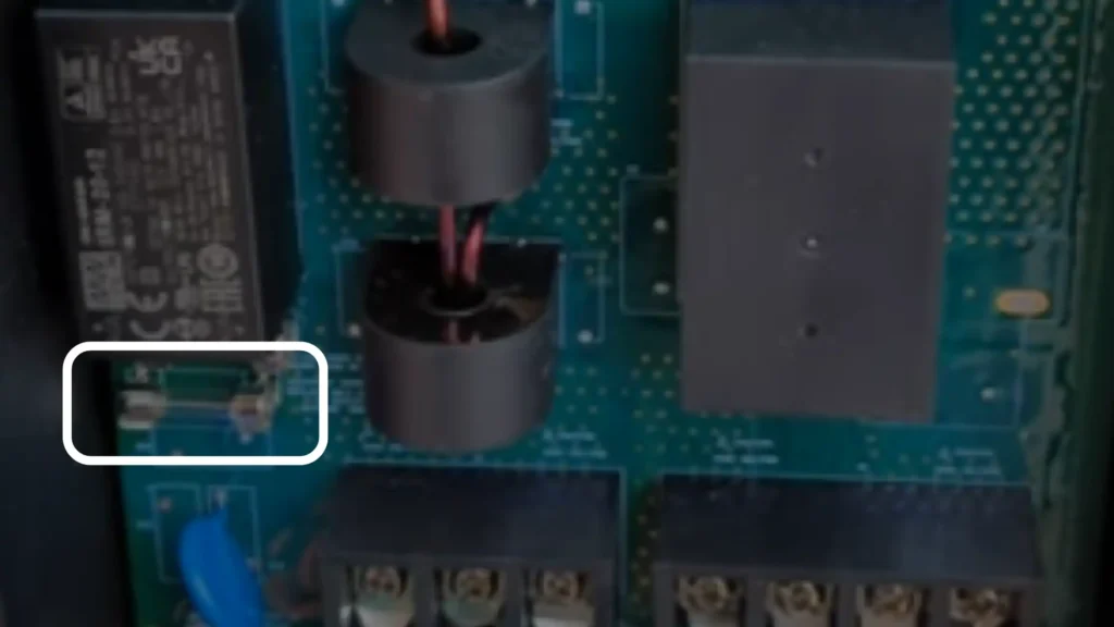 A close-up internal view of a green circuit board within a Grizzl-E Smart EV charger. A clear white box highlights a small, cylindrical glass fuse horizontally mounted on the PCB, serving as a critical overcurrent protection device.