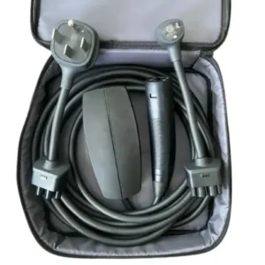 This image shows the Tesla Gen 3 Mobile Connector portable charging kit neatly organized inside its open, gray zippered storage bag. The kit is displayed on a clean white background, clearly presenting the components included with Tesla’s latest-generation portable EV charging solution. A long, heavy-duty black charging cable is carefully coiled around the inner perimeter of the bag. The thick insulation and flexible design highlight the cable’s durability and its intended use for both Level 1 and Level 2 portable charging. Positioned toward the center-left of the bag is the compact matte-black controller unit, commonly referred to as the charging “brick.” This housing contains the core EVSE electronics that regulate power delivery, communicate with the vehicle, and monitor safety conditions during charging. On the center-right side sits the ergonomic vehicle connector handle featuring Tesla’s North American Charging Standard (NACS) plug. The handle’s streamlined shape and integrated control button are designed for easy one-handed connection and removal from compatible Tesla charge ports. At the top of the kit are two interchangeable plug adapters used to connect the Gen 3 Mobile Connector to different power sources. On the top left is the NEMA 14-50 adapter, a 240-volt plug commonly used for RV outlets and high-power residential circuits. On the top right is the NEMA 5-15 adapter, the standard 120-volt household plug used for Level 1 charging. The entire Tesla Gen 3 Mobile Connector kit is designed as a portable charging solution that can be stored in a vehicle’s trunk, giving Tesla owners the flexibility to charge from a variety of outlets while traveling or away from home.