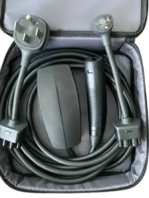 This image shows the Tesla Gen 3 Mobile Connector portable charging kit neatly organized inside its open, gray zippered storage bag. The kit is displayed on a clean white background, clearly presenting the components included with Tesla’s latest-generation portable EV charging solution. A long, heavy-duty black charging cable is carefully coiled around the inner perimeter of the bag. The thick insulation and flexible design highlight the cable’s durability and its intended use for both Level 1 and Level 2 portable charging. Positioned toward the center-left of the bag is the compact matte-black controller unit, commonly referred to as the charging “brick.” This housing contains the core EVSE electronics that regulate power delivery, communicate with the vehicle, and monitor safety conditions during charging. On the center-right side sits the ergonomic vehicle connector handle featuring Tesla’s North American Charging Standard (NACS) plug. The handle’s streamlined shape and integrated control button are designed for easy one-handed connection and removal from compatible Tesla charge ports. At the top of the kit are two interchangeable plug adapters used to connect the Gen 3 Mobile Connector to different power sources. On the top left is the NEMA 14-50 adapter, a 240-volt plug commonly used for RV outlets and high-power residential circuits. On the top right is the NEMA 5-15 adapter, the standard 120-volt household plug used for Level 1 charging. The entire Tesla Gen 3 Mobile Connector kit is designed as a portable charging solution that can be stored in a vehicle’s trunk, giving Tesla owners the flexibility to charge from a variety of outlets while traveling or away from home.