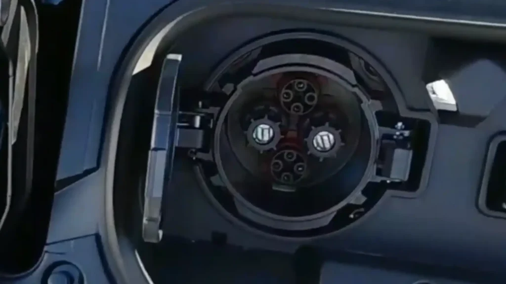 A close-up view of an open CHAdeMO charging port on a dark blue electric vehicle, showing the internal pin layout and circular socket.